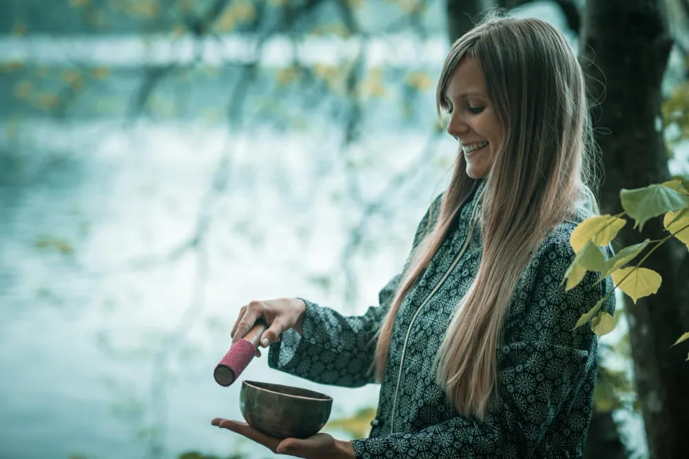smiling-young-woman-holding-bowl-by-lake
