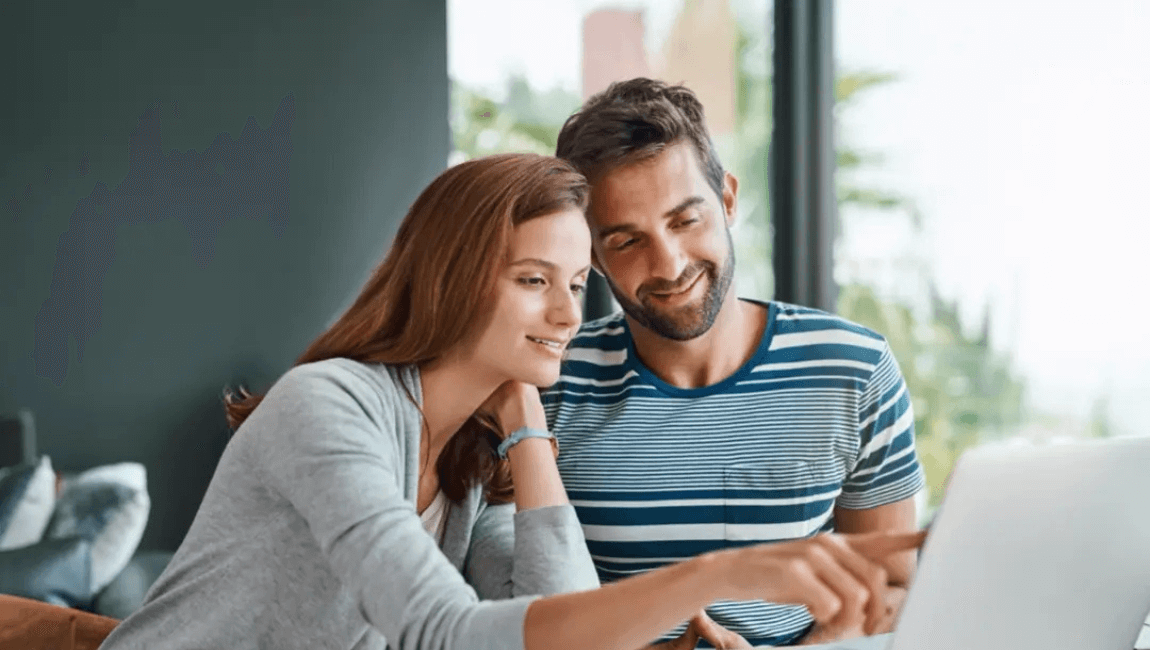 A man and woman collaborate while looking at a laptop screen together, sharing ideas and insights